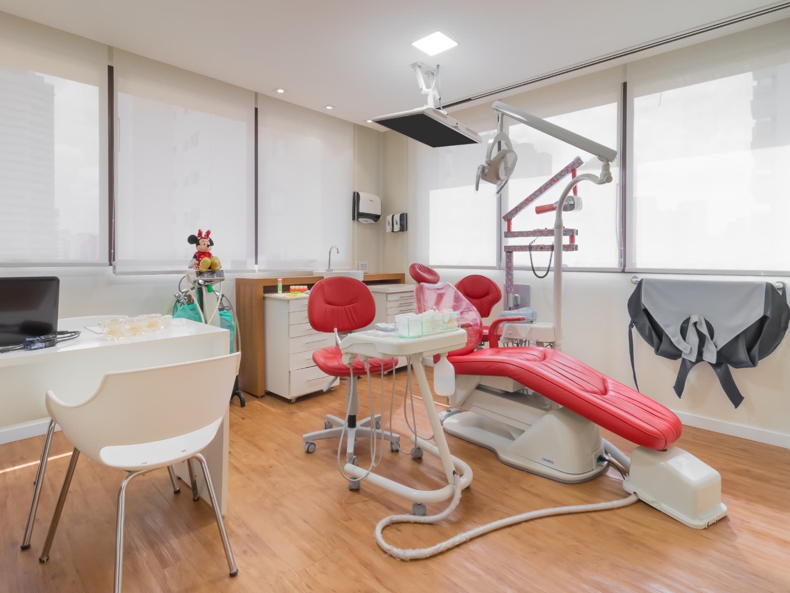 Consultório com cadeira vermelha e ambiente iluminado por luz natural